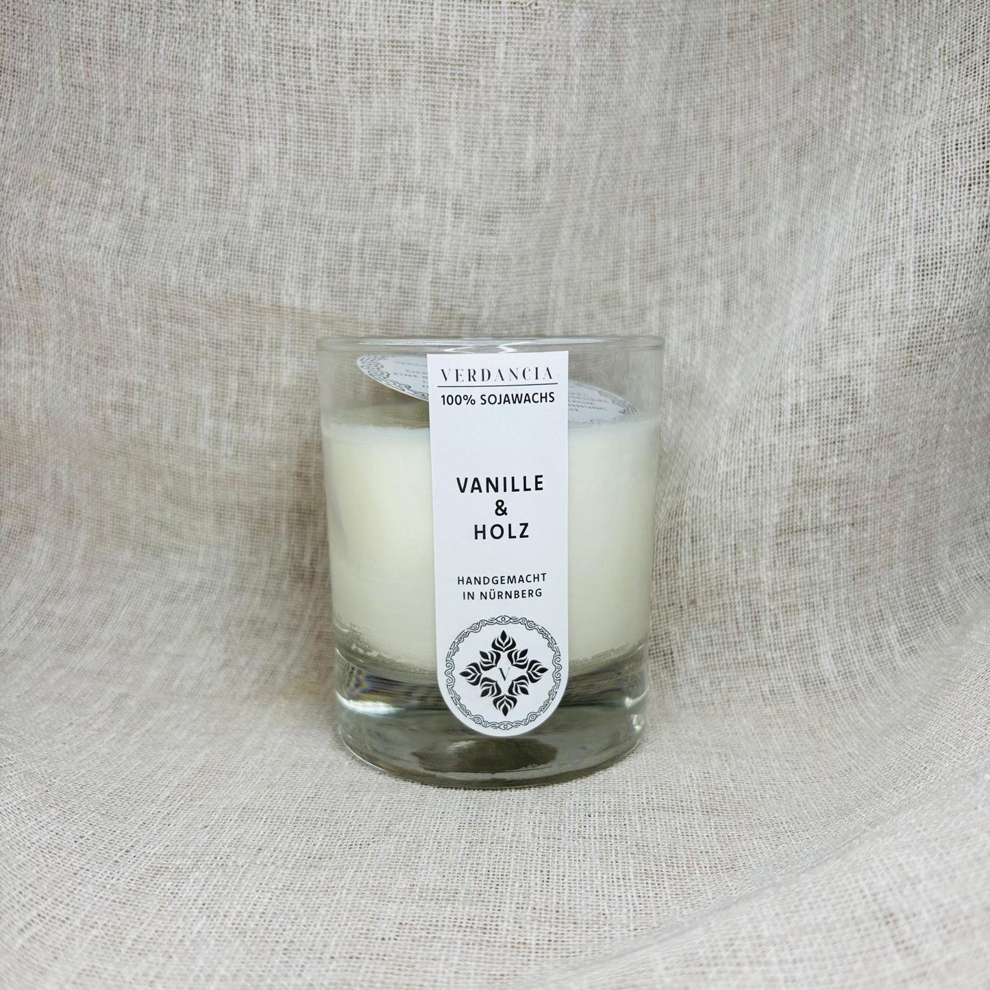 Verdancia Soja Duftkerze in Vanille & Holz, showcasing a sleek design and warm glow in a cozy setting.