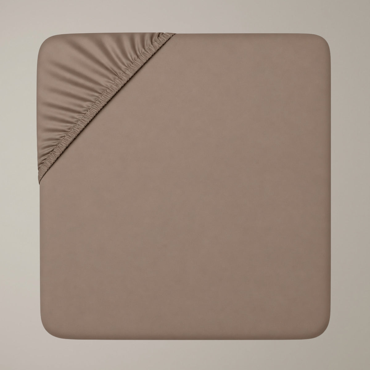 Draufsicht auf ein taupefarbenes Finole Luxe Satin-Spannbettlaken aus ägyptischer Baumwolle, das eine elastische Ecke zeigt.