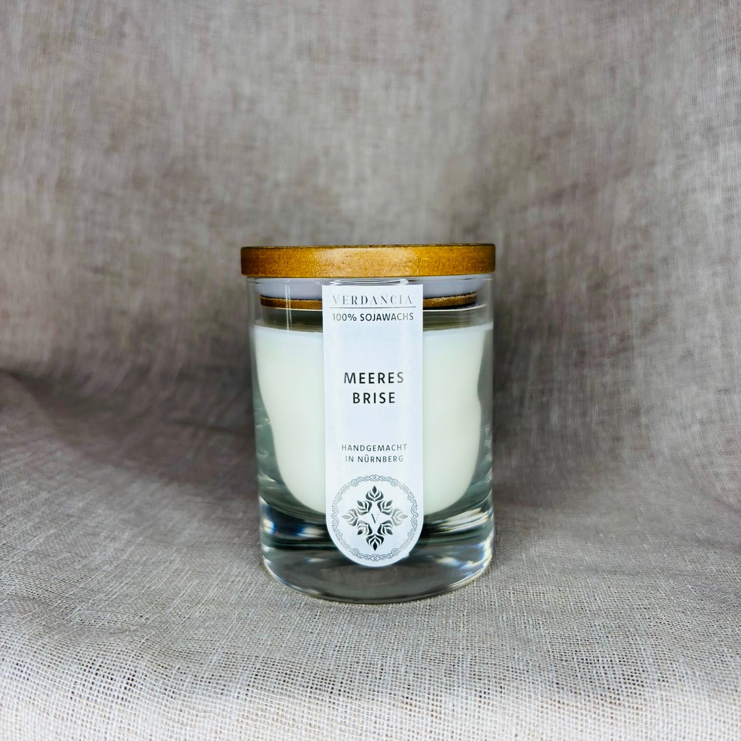 Duftkerze "Meeresbrise" von Verdancia mit Holz, Salbei und Meersalz, brennend in elegantem Glasbehälter.