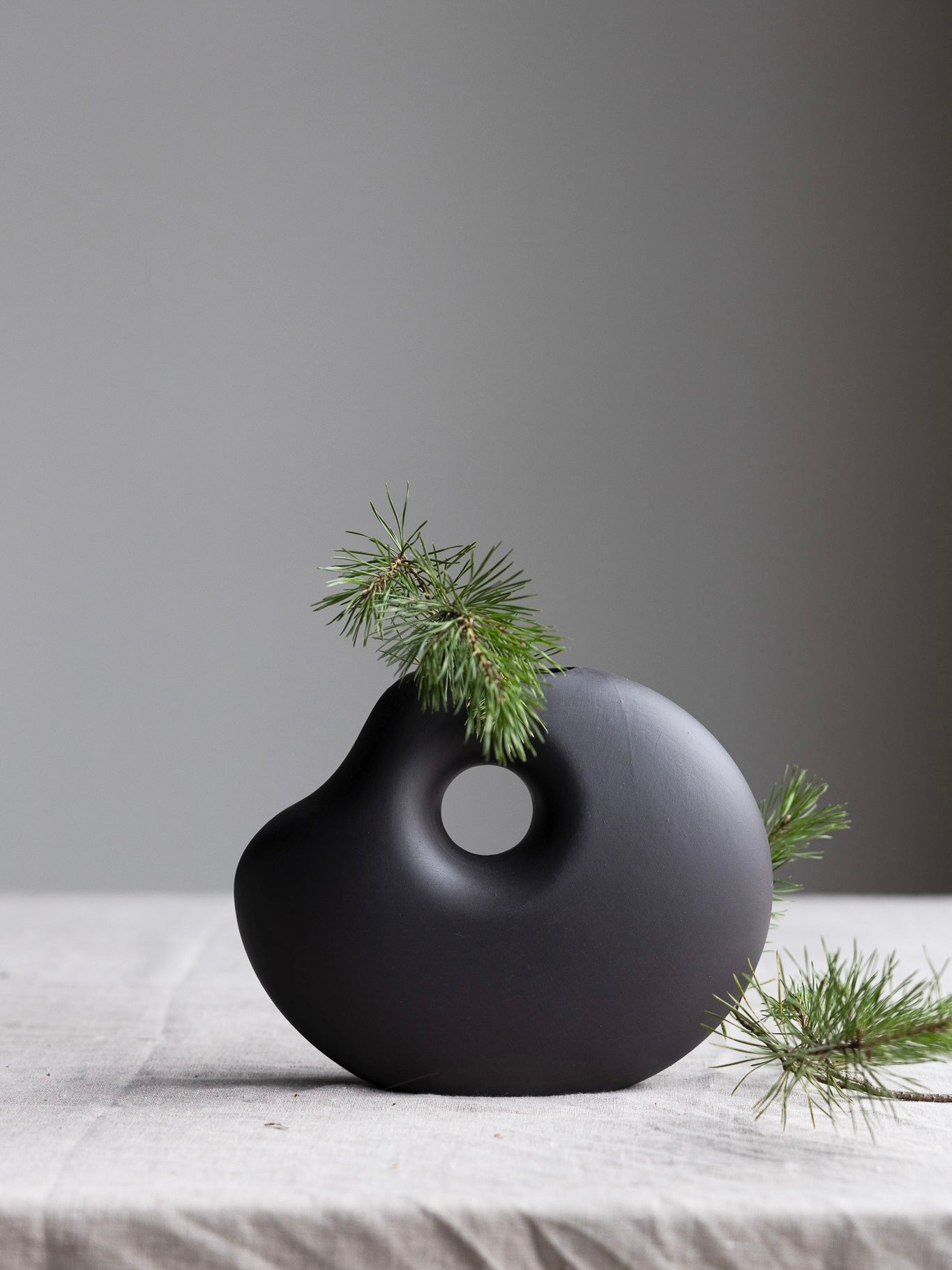 Dunkelgraue Keramikvase „Lunden“ von Storefactory, handgefertigt im Retro-Design, H19 cm, auf einem Tisch platziert