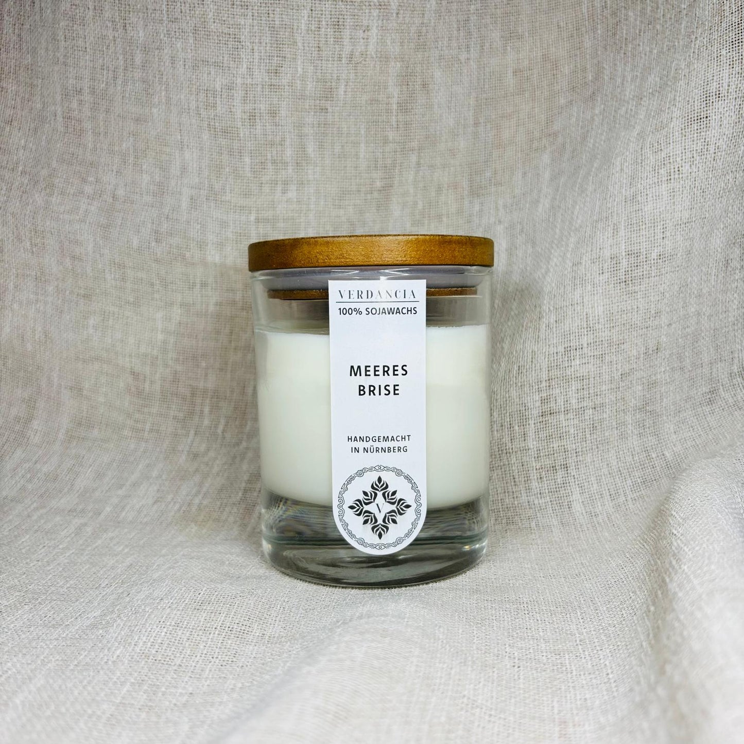 Duftkerze "Meeresbrise" von Verdancia mit Holz, Salbei und Meersalz, zeigt brennende Sojakerze in einem eleganten Glas.